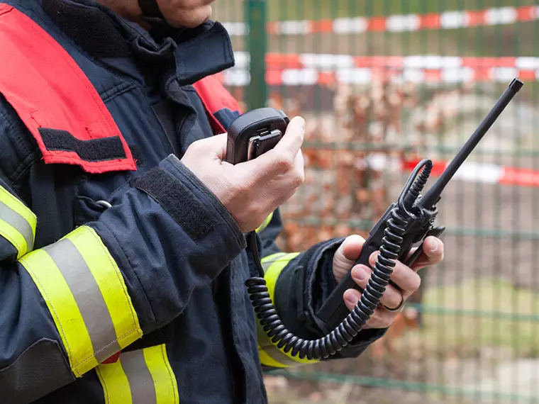 Public Safety application - Fireman in a red vest holding a portable radio