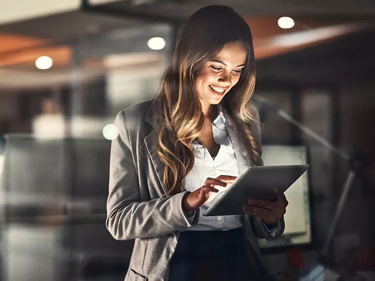 Wi-Fi application - Woman in business attire using a tablet computer in a dark room